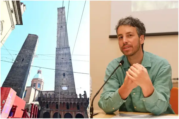 Le torri Asinelli e Garisenda a Bologna, con una cupola in mezzo, e un uomo che parla al microfono.