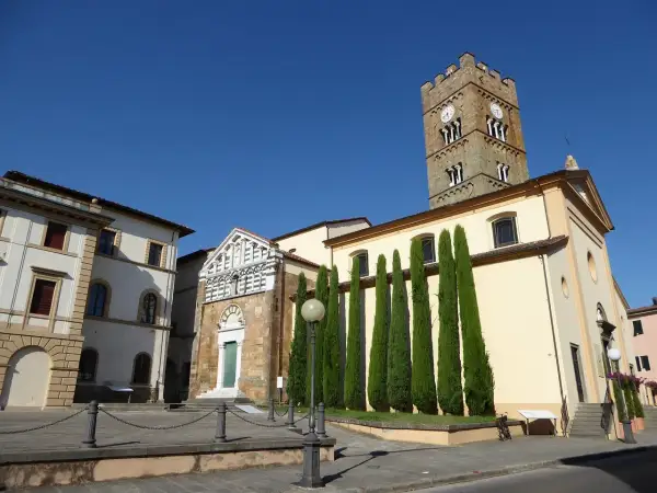 Piazza ad Altopascio dove si trova la chiesa con campanile medievale e cipressi slanciati.