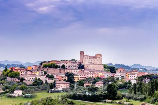 Borgo medievale arroccato sulla collina nella valle del Rubicone, con un imponente castello e case colorate.