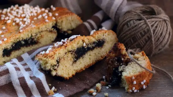 Fette di dolci emiliani con ripieno scuro, guarnite con zuccherini, su un tovagliolo a righe.