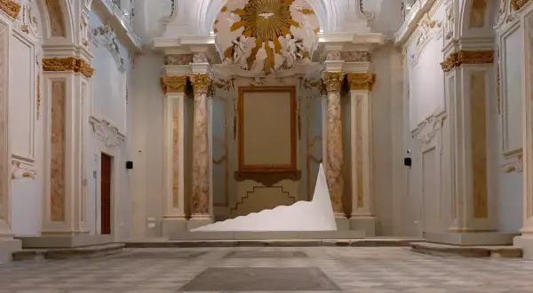 Installazione moderna in un ambiente storico, tra i musei di Livorno. Una scultura bianca a forma di onda domina la scena.
