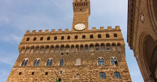 Palazzo Vecchio, simbolo di Firenze medievale, con la sua torre imponente e gli stemmi araldici.