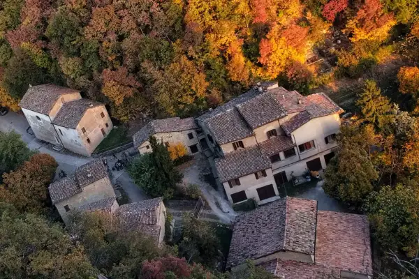 Borgo autunnale a Montale PT, Italia, con case in pietra e tetti in cotto immerse nel foliage colorato.