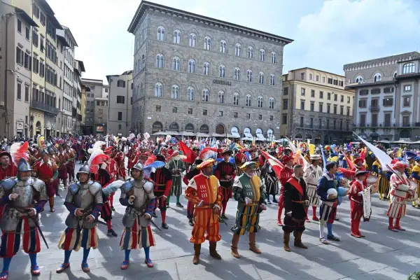 Sfilata storica a San Giovanni, Firenze. Uomini in costume rinascimentale, con armature e bandiere, celebrano la festa.