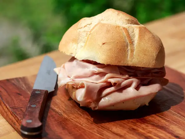 Panino con mortadella su tagliere di legno, un'ottima idea per sapere dove fermarsi tra Bologna e Firenze.