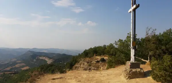 Croce in cima a un crinale roccioso, con un panorama mozzafiato sulle montagne dell'Emilia Romagna.