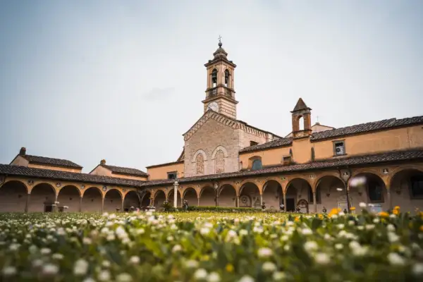 Cortile con portico ad archi e campanile, immerso in un prato fiorito. Un luogo sereno sul monte Senario.