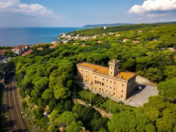 Castiglioncello cosa vedere: un castello imponente circondato da una pineta rigogliosa, con il mare all'orizzonte.