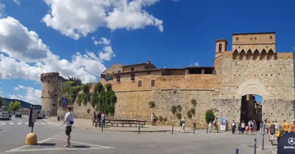 La **Siena Fortezza Medicea** domina il paesaggio con le sue mura imponenti. Turisti passeggiano sotto il sole, ammirando la storia.