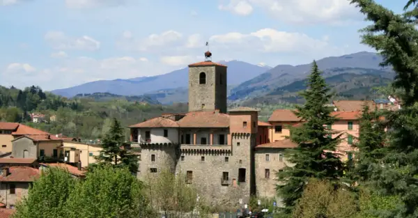 La Rocca Ariostesca domina il borgo con la sua torre imponente, circondata da case dai tetti rossi e verdi colline.